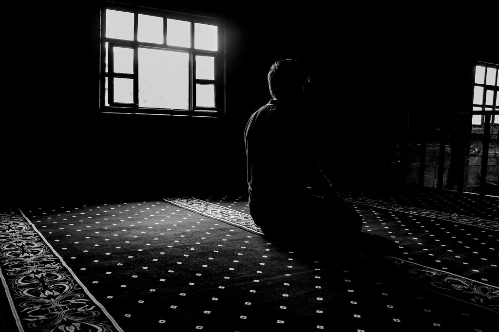 man praying in darkness at mosque