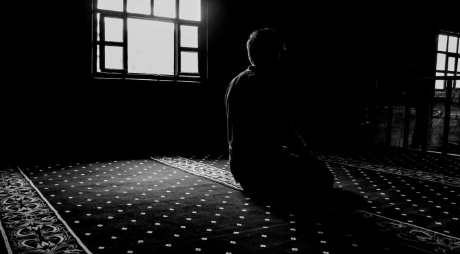 man praying in darkness at mosque