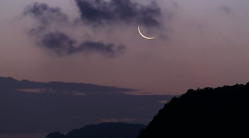 silhouette of mountain under the moon covered with clouds