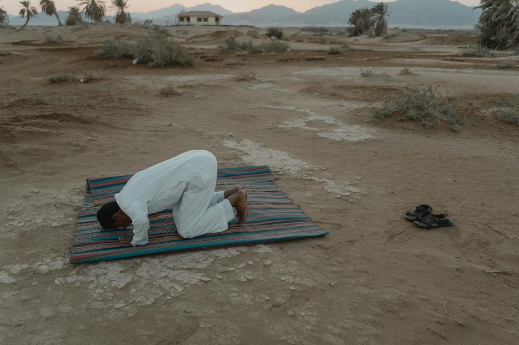 photo of man bowing on mat during dawn