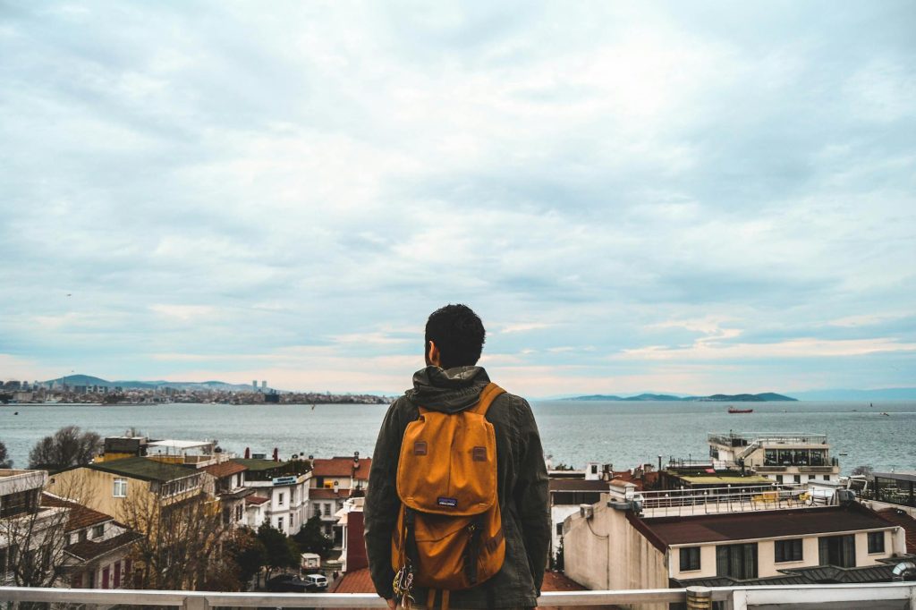 man wearing black jacket and brown backpack
