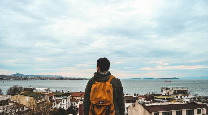 man wearing black jacket and brown backpack