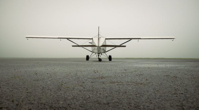 A solitary small aircraft captured on a foggy airport runway, showcasing aviation serenity.