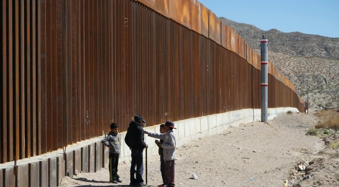 children standing next to borderline wall