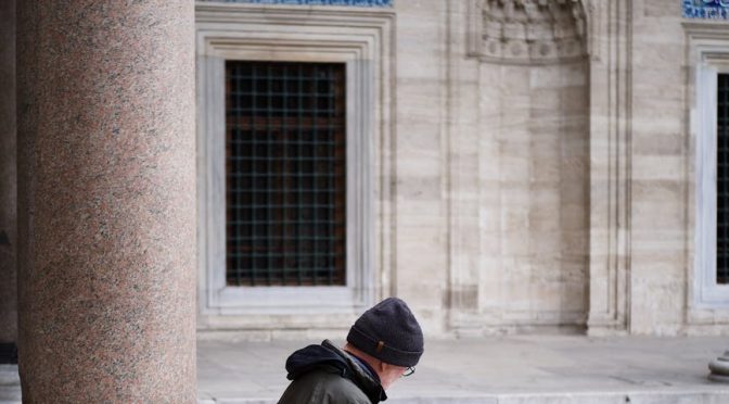 man sitting in front of a mosque