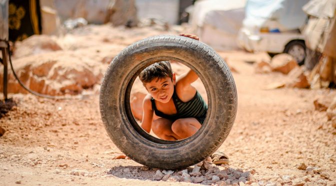 a boy looking through a tire s hole