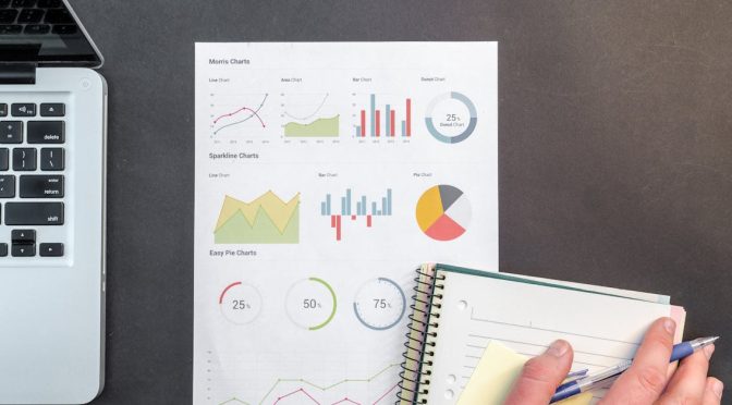 Overhead view of a business desk with charts and a laptop, ideal for data analysis concepts.